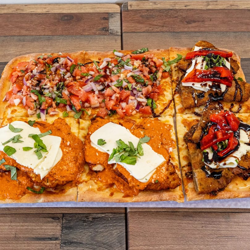 Pizza Chop's rectangular pizza with bruschetta, chicken parmesan, and roasted pepper toppings.